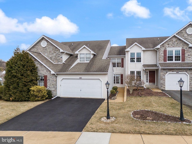 view of front facade featuring stone siding, roof with shingles, aphalt driveway, and stucco siding