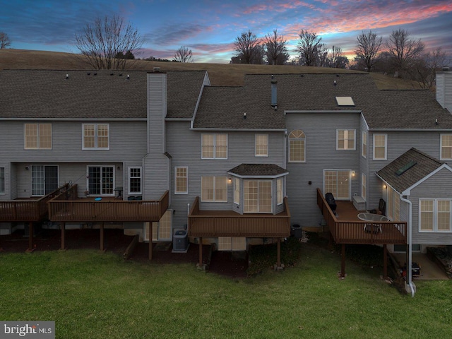 back of house featuring a deck, cooling unit, a lawn, and a chimney