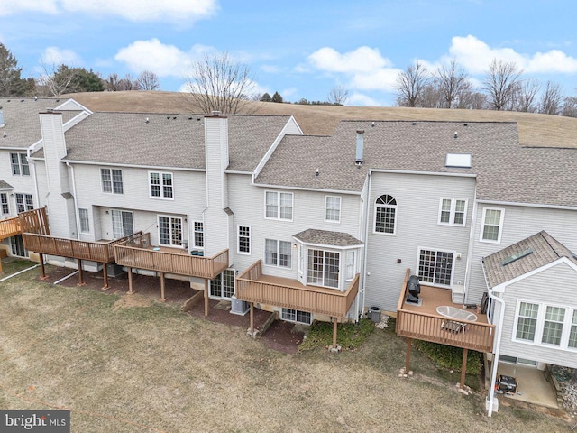 back of house with roof with shingles, a chimney, cooling unit, and a wooden deck