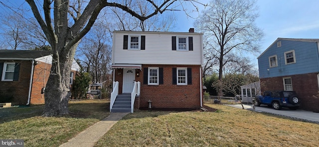 view of front facade with a chimney, a front lawn, and brick siding