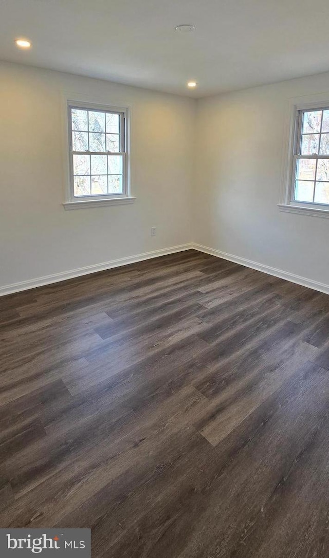 spare room with dark wood-type flooring, recessed lighting, and baseboards