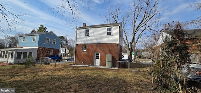 rear view of house with a chimney, brick siding, a lawn, and a fenced backyard