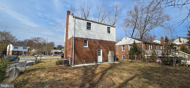 rear view of property with central AC, brick siding, a lawn, and fence