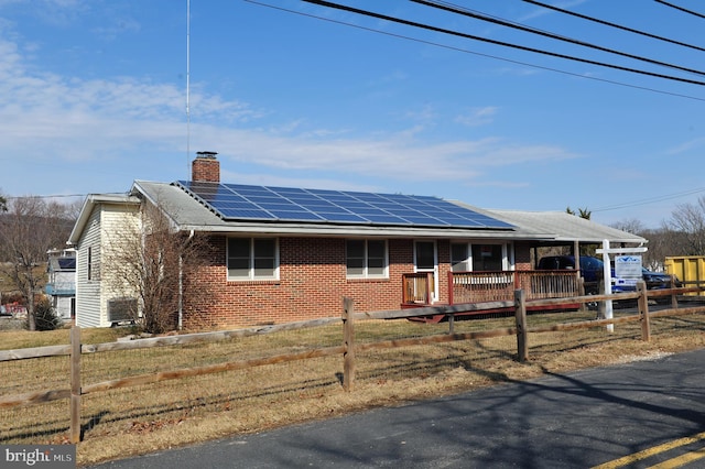 single story home with a fenced front yard, brick siding, and roof mounted solar panels