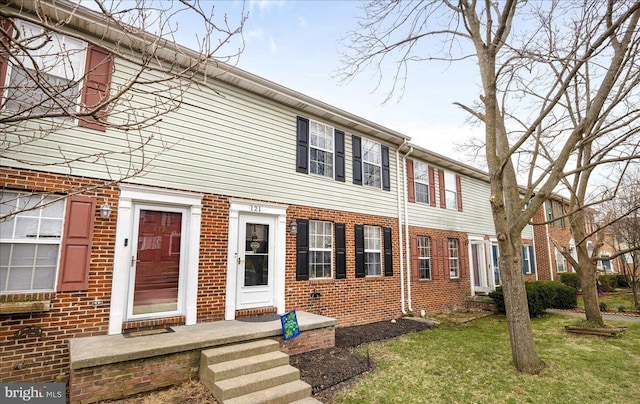 view of property with brick siding and a front yard