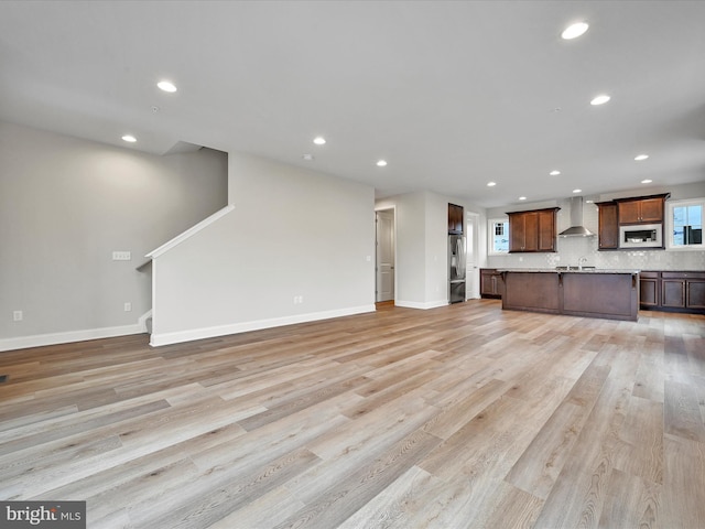 unfurnished living room with baseboards, recessed lighting, and light wood-style floors