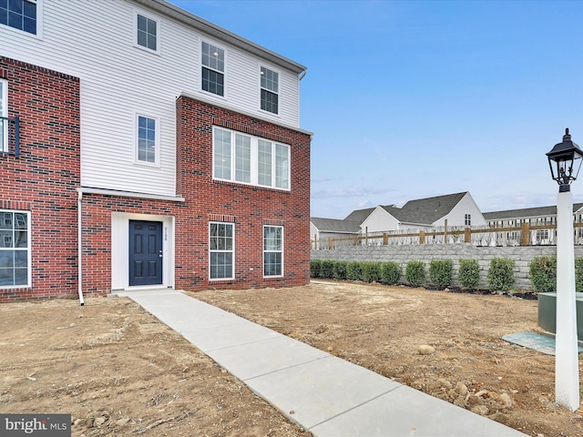 view of front of house featuring brick siding and fence