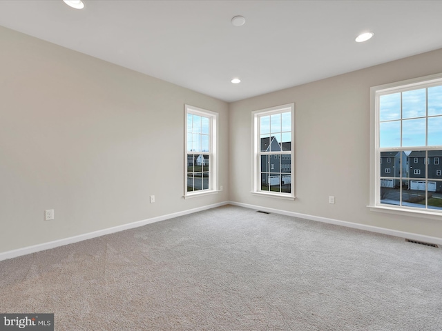 carpeted empty room with baseboards, visible vents, and recessed lighting