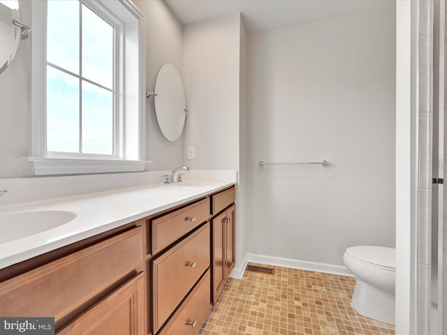 bathroom with double vanity, baseboards, visible vents, toilet, and a sink