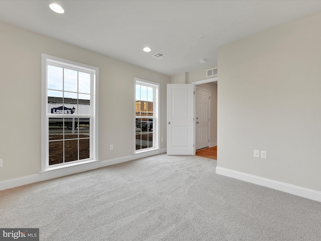 carpeted empty room with baseboards, visible vents, and recessed lighting