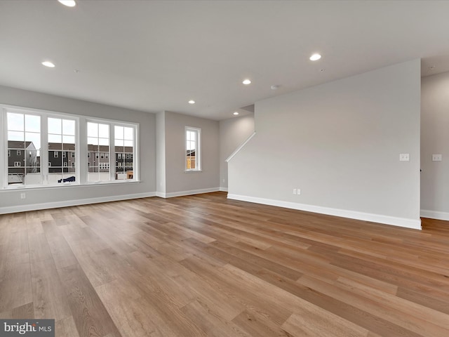 unfurnished living room with baseboards, light wood finished floors, and recessed lighting