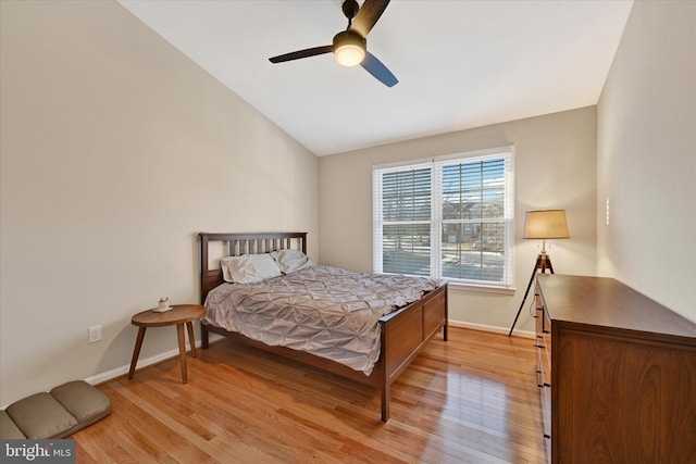 bedroom featuring light wood finished floors, ceiling fan, baseboards, and vaulted ceiling