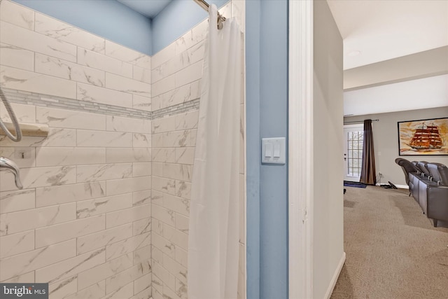 bathroom with a tile shower and baseboards