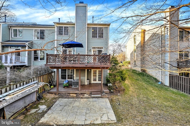 back of house featuring a patio, a chimney, a lawn, central AC, and a wooden deck