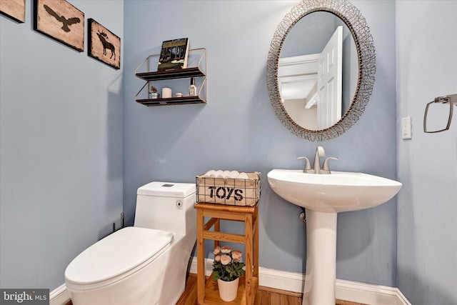 bathroom with baseboards, toilet, and wood finished floors