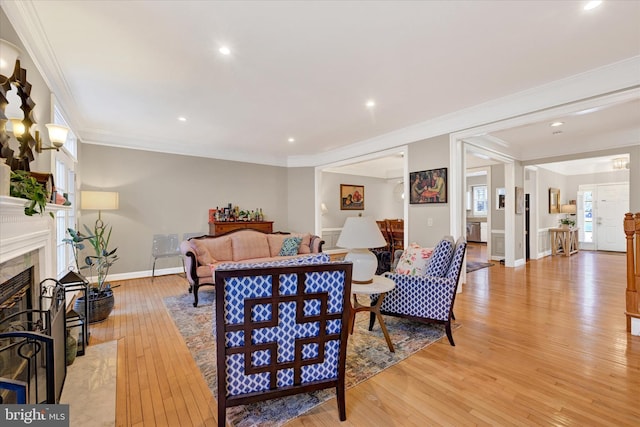 living room with recessed lighting, a high end fireplace, baseboards, light wood-style floors, and crown molding