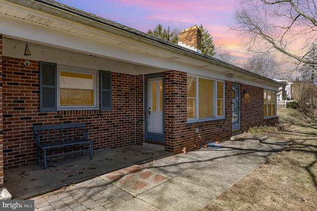 exterior space with brick siding and a chimney