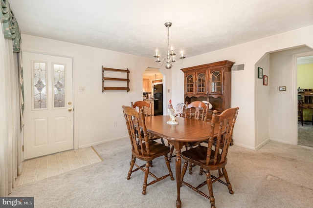 dining room with baseboards, arched walkways, an inviting chandelier, and light carpet