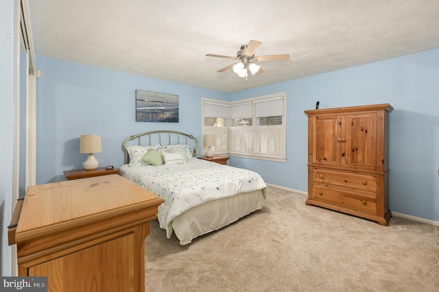 bedroom featuring baseboards, light colored carpet, and a ceiling fan