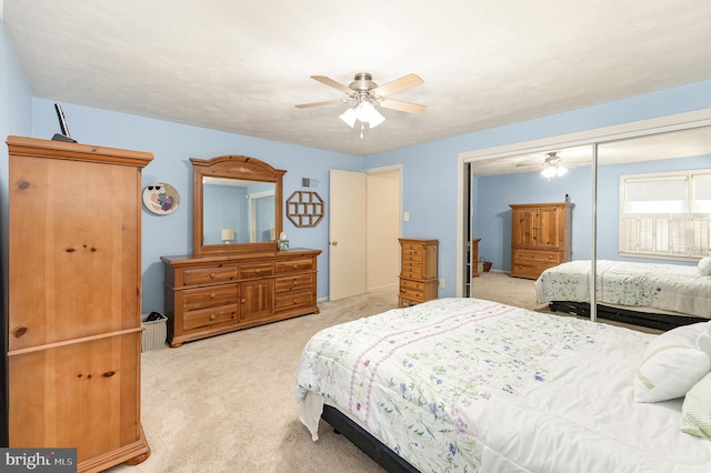 bedroom with a ceiling fan, light colored carpet, and a closet