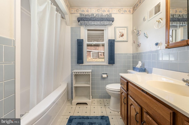 full bath with vanity, a wainscoted wall, visible vents, tile walls, and toilet