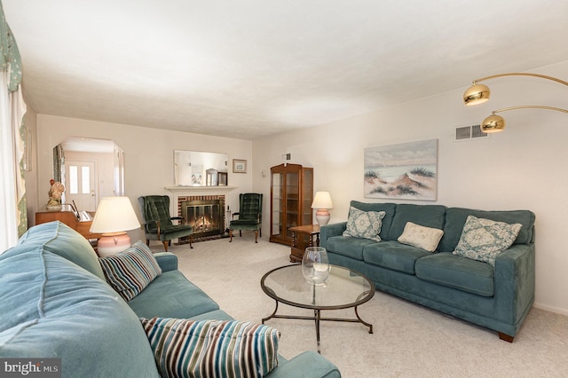 living area with a fireplace, carpet, visible vents, and arched walkways