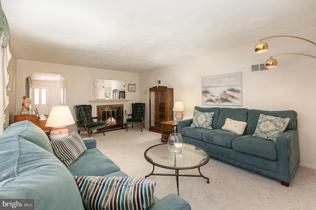 carpeted living room featuring visible vents, arched walkways, and a brick fireplace