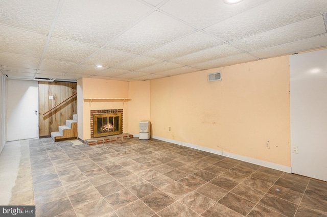 unfurnished living room with visible vents, a brick fireplace, stairs, and a paneled ceiling