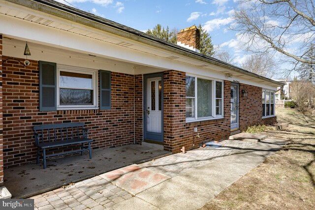 exterior space featuring brick siding and a chimney