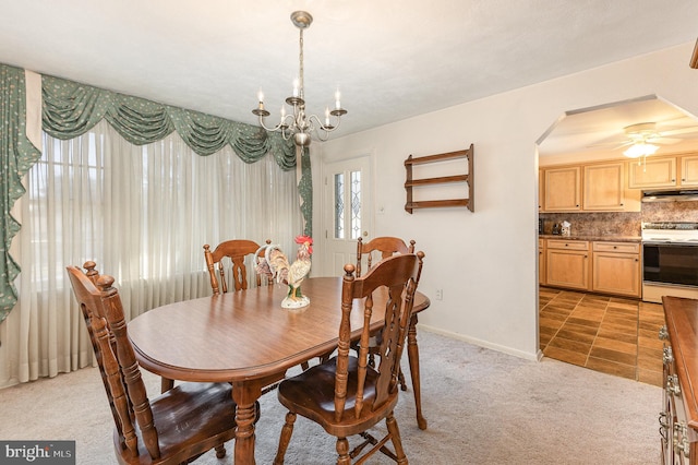 dining room with arched walkways, light colored carpet, ceiling fan with notable chandelier, and baseboards