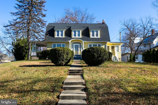 view of front of home with roof with shingles, a chimney, and a front lawn