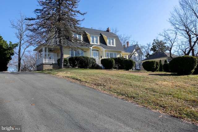 colonial inspired home with a chimney, a front lawn, and a porch