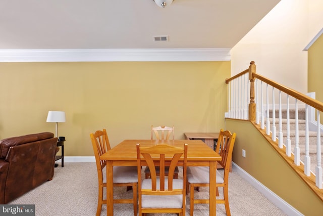 carpeted dining area with crown molding, stairway, visible vents, and baseboards