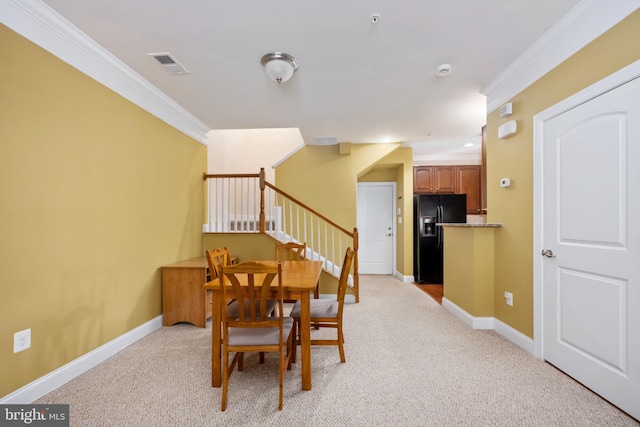 dining room featuring light carpet, crown molding, baseboards, and stairs