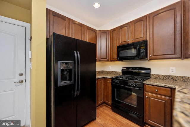 kitchen featuring light stone countertops, black appliances, light wood finished floors, and recessed lighting