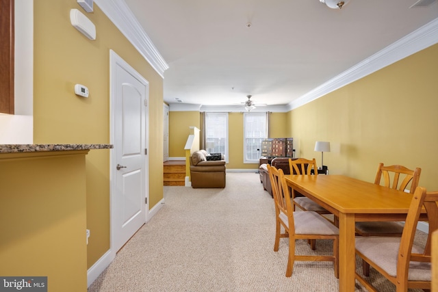 dining room with ornamental molding, light colored carpet, ceiling fan, and baseboards