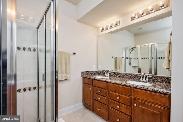 full bathroom featuring double vanity, a stall shower, a sink, and tile patterned floors