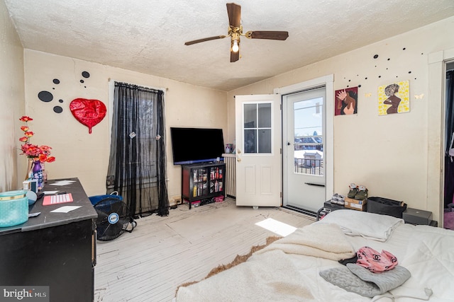 bedroom with ceiling fan, a textured ceiling, wood finished floors, and access to outside