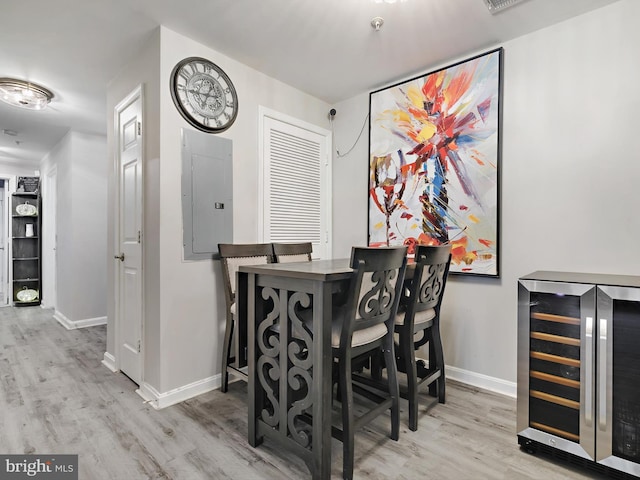 dining room featuring wine cooler, electric panel, baseboards, and wood finished floors