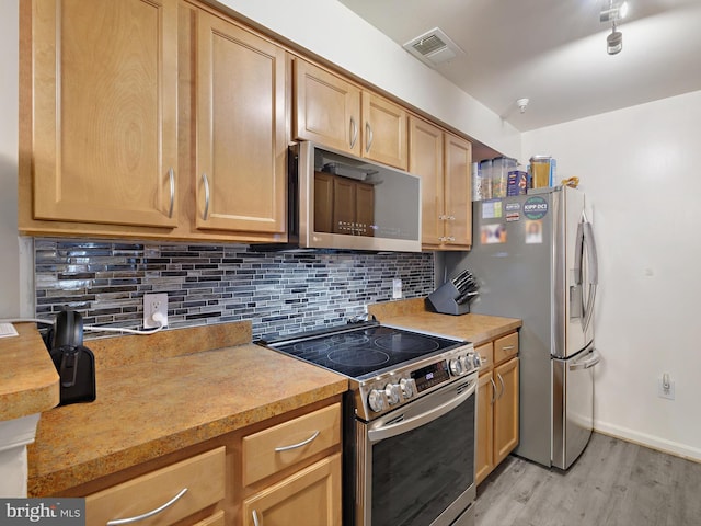 kitchen featuring stainless steel appliances, visible vents, light wood-style floors, light countertops, and decorative backsplash