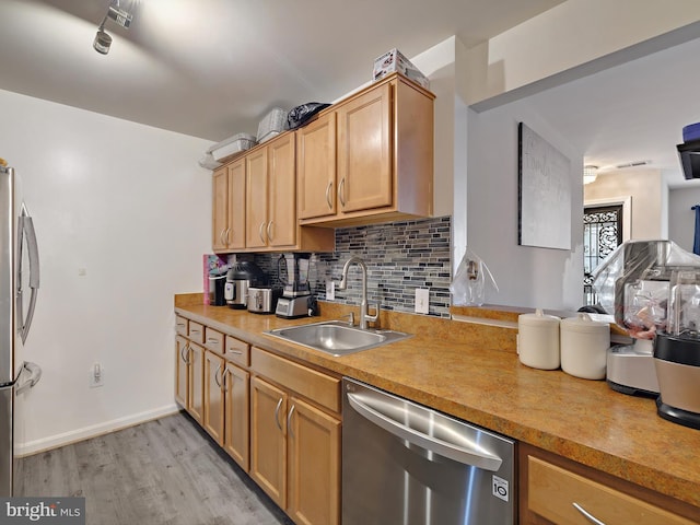 kitchen featuring light countertops, backsplash, appliances with stainless steel finishes, a sink, and light wood-type flooring