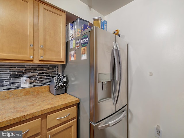 kitchen featuring stainless steel refrigerator with ice dispenser, backsplash, and light countertops