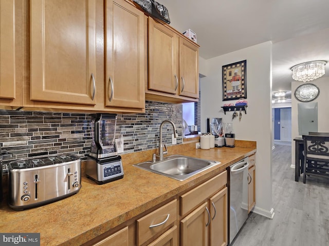 kitchen with a sink, light countertops, stainless steel dishwasher, backsplash, and light wood finished floors