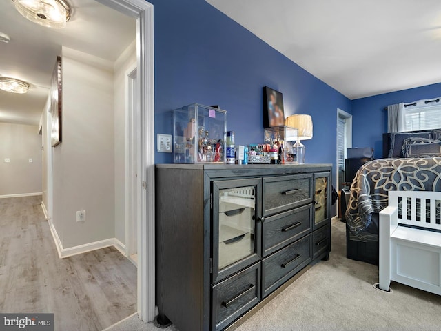 bedroom featuring a dry bar, light wood-style flooring, and baseboards