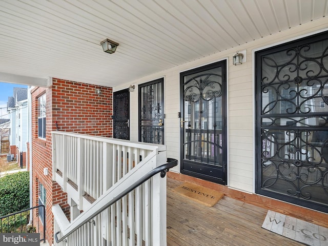 entrance to property featuring a porch and brick siding