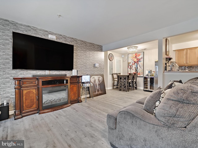 living area featuring beverage cooler, a glass covered fireplace, wood finished floors, and baseboards