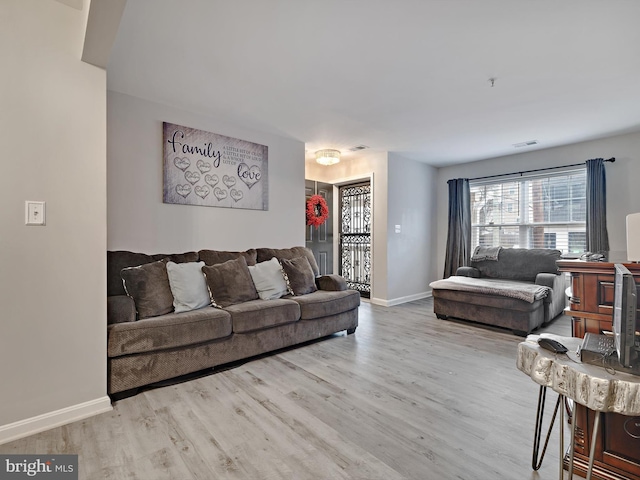 living room featuring baseboards, visible vents, and wood finished floors