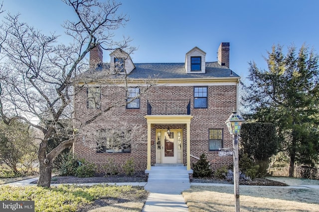 georgian-style home with a chimney and brick siding