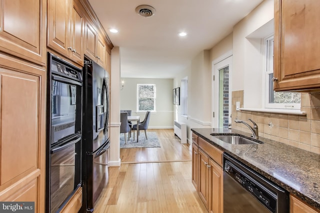 kitchen featuring tasteful backsplash, radiator, a sink, dark stone countertops, and black appliances