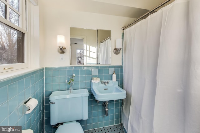 full bathroom featuring tile walls, toilet, wainscoting, a sink, and a shower with curtain